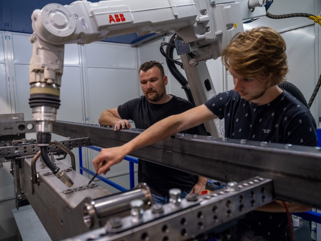 Een ervaren medewerker van We-Metal uit Renswoude begeleidt een leerling