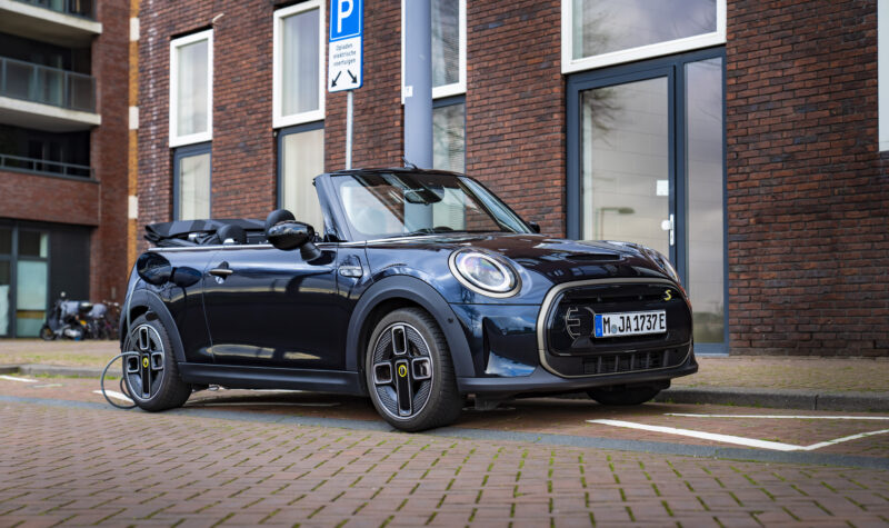 De MINI Cabrio Electric van BMW op een parkeerplaats aan een laadpaal